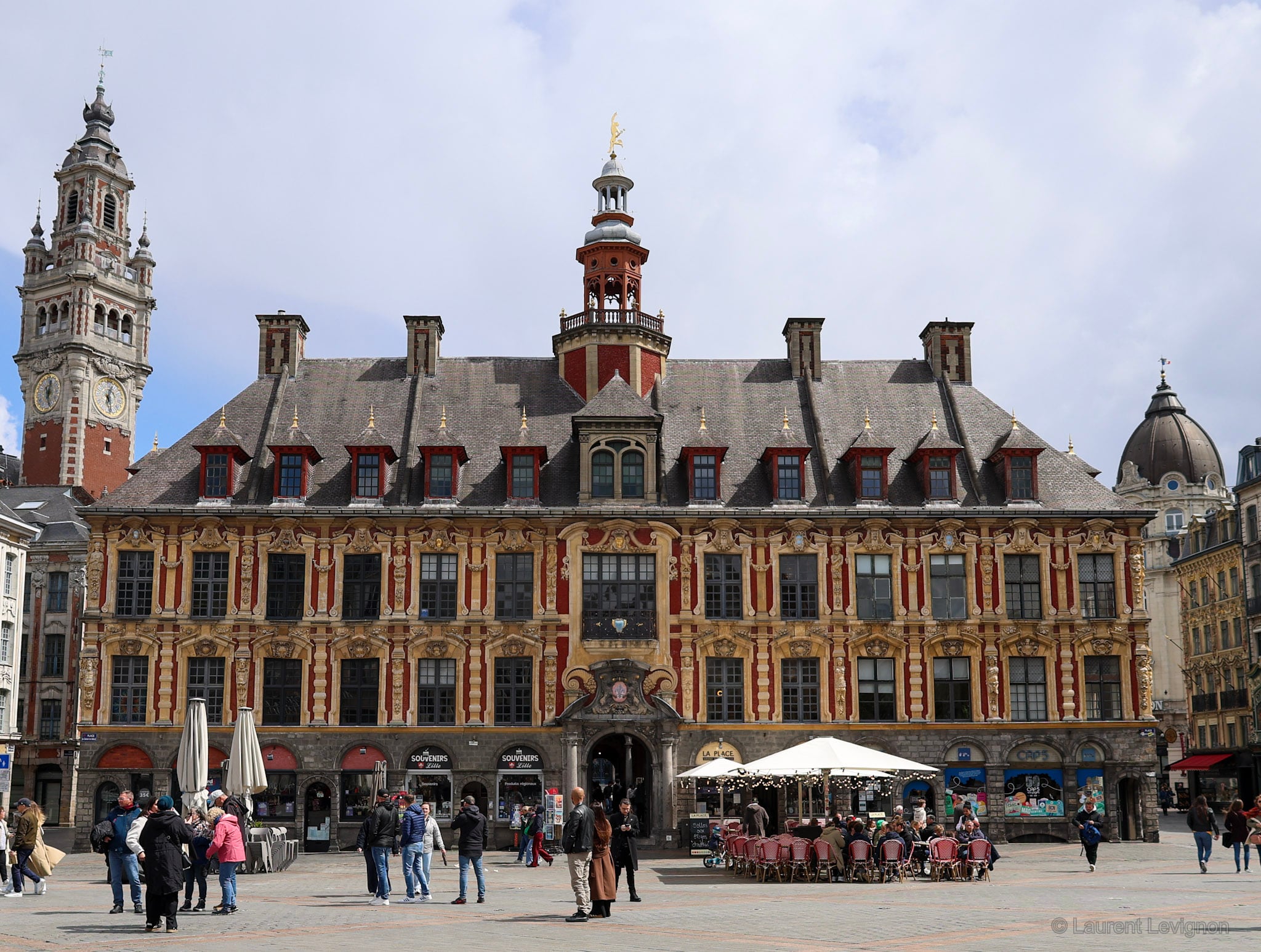 Lille, mai 2026. Vingt-quatre maisons identiques autour d'une cour, bâties en 1653 par Julien Destrée ; Mercure, dieu du commerce, couronne le campanile. À gauche, le beffroi de Cordonnier.
