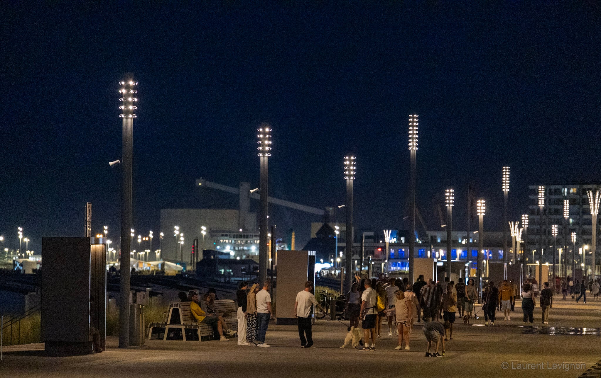 Calais, un soir d'août. Les mâts lumineux du front de mer réaménagé, et la digue qui ne se vide pas.