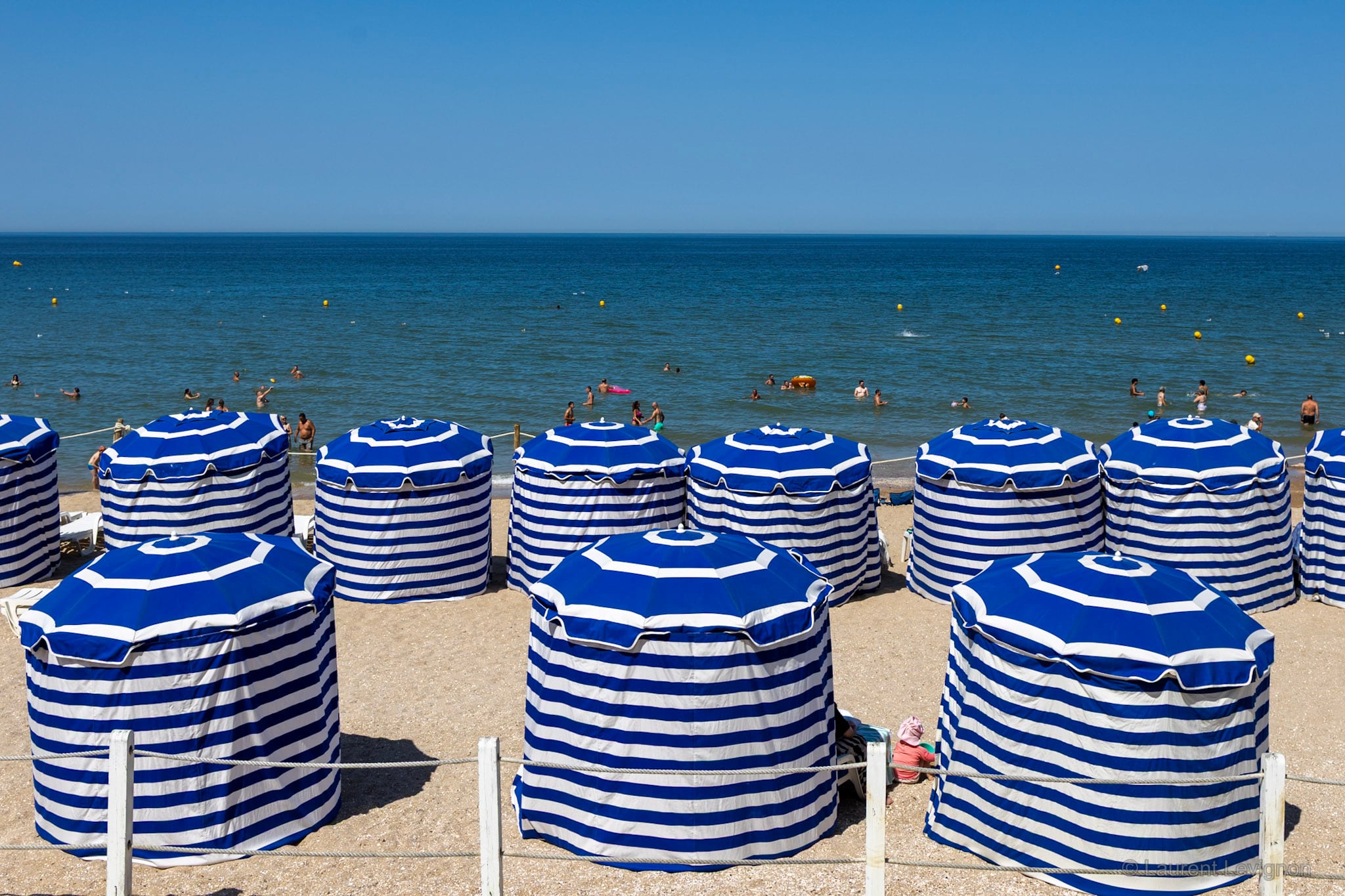 Les tentes à rayures de la plage de Cabourg, sous la promenade Marcel-Proust. Août 2026.