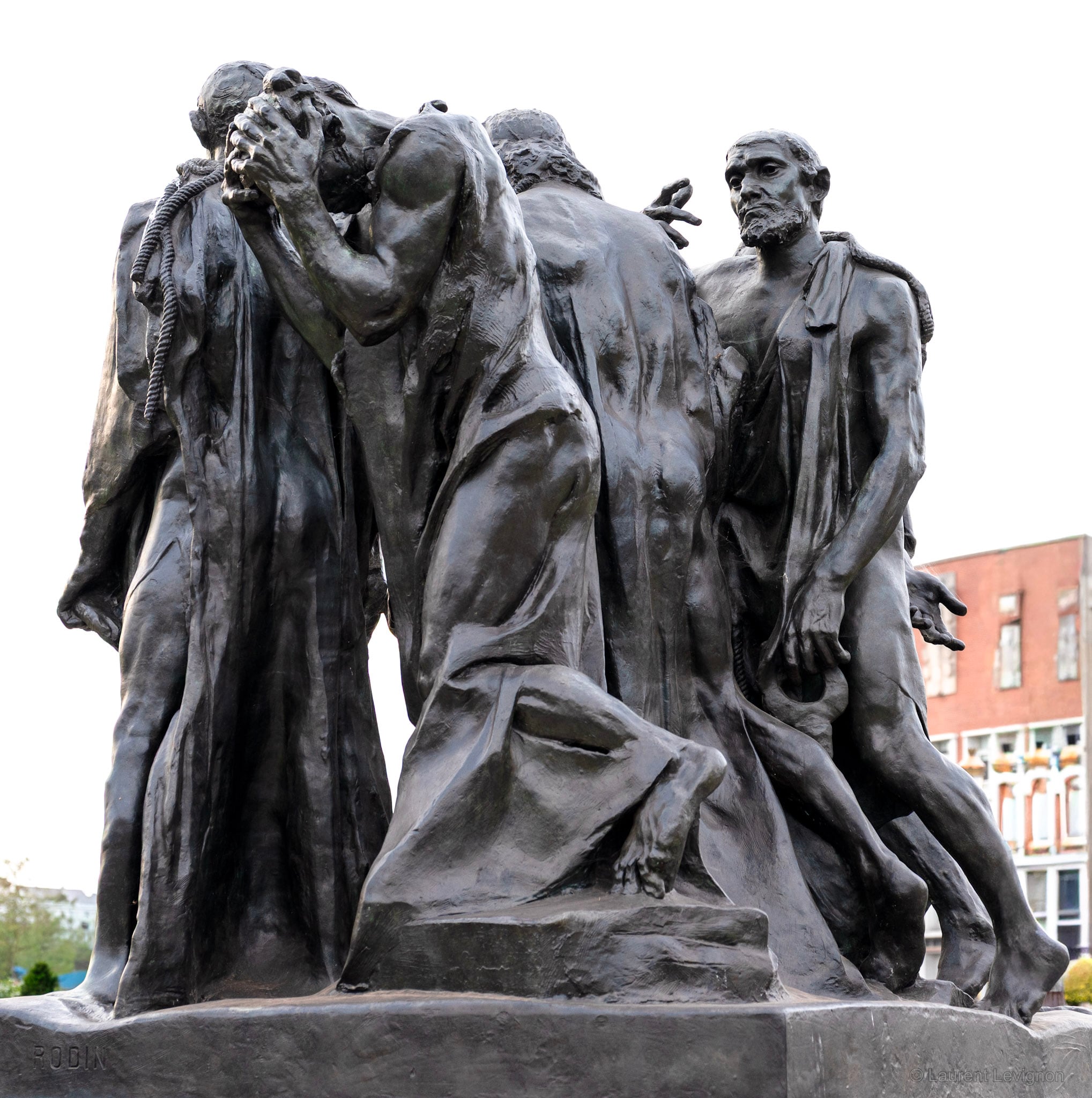 Vu de dos, le groupe de Rodin montre ce que la face cache : le désespoir de l'un, la tête dans les mains. La signature du sculpteur se lit sur le socle. Calais, octobre 2026.